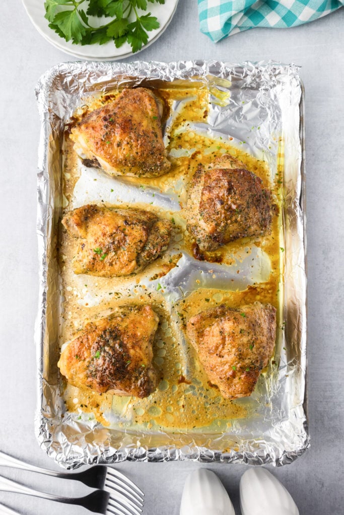 Crispy brown baked chicken thighs in a ranch seasoning on a foil-lined baking tray after baking.