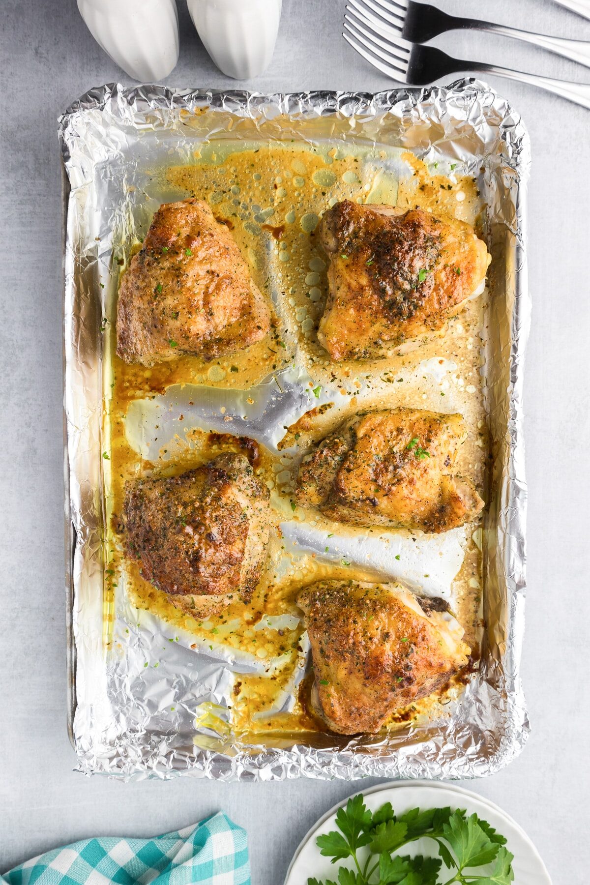 Crispy brown baked chicken thighs in a ranch seasoning on a foil-lined baking tray after baking.