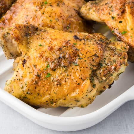 Golden-brown roasted ranch chicken thighs seasoned on a white serving platter.