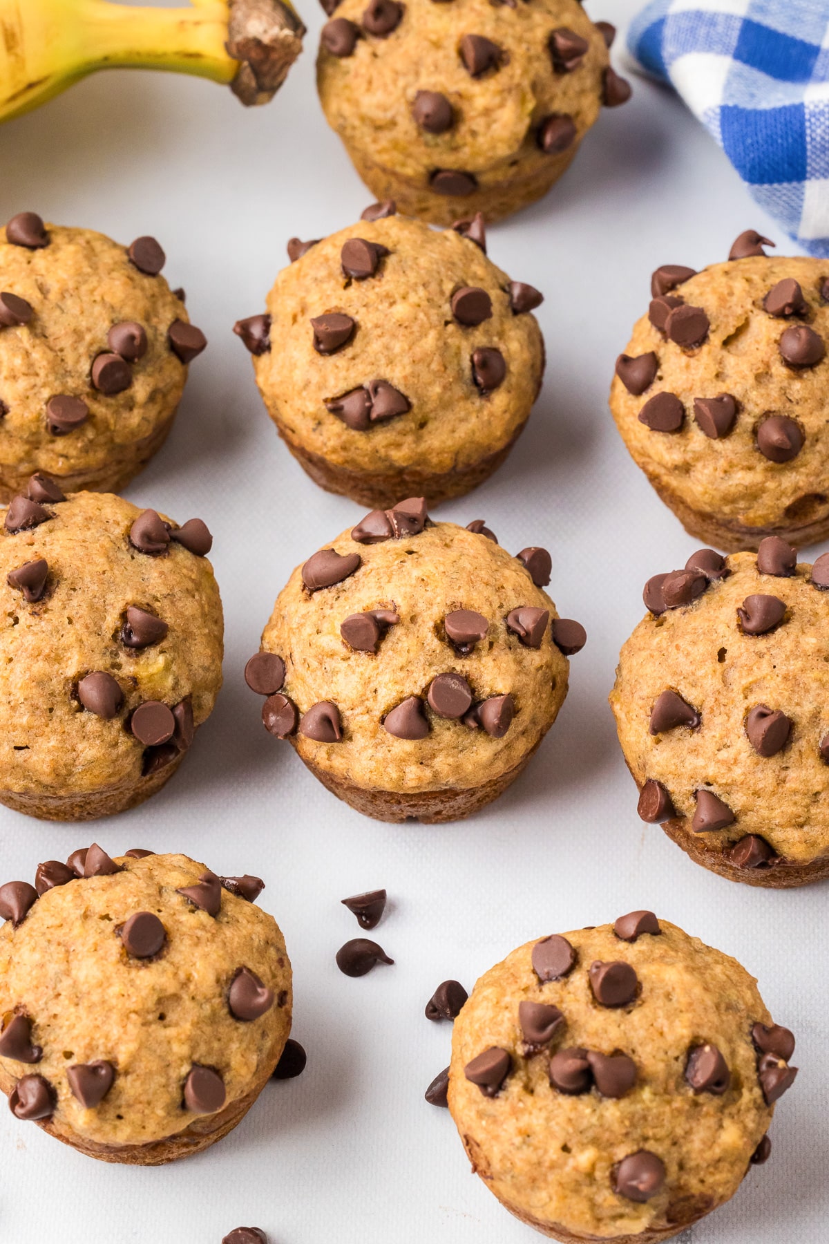 Freshly baked mini banana chocolate chip muffins on a counter from above.