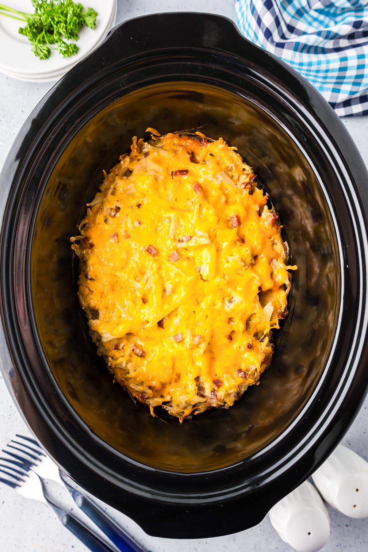 Cheesy slow cooker hashbrown casserole in the base of a crockpot after cooking.