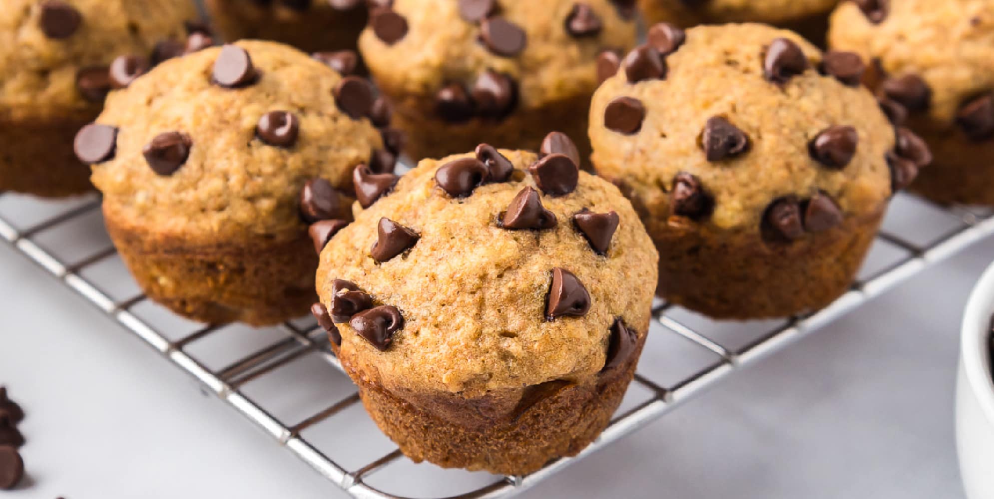 Freshly baked mini banana chocolate chip muffins cooling on a wire rack.