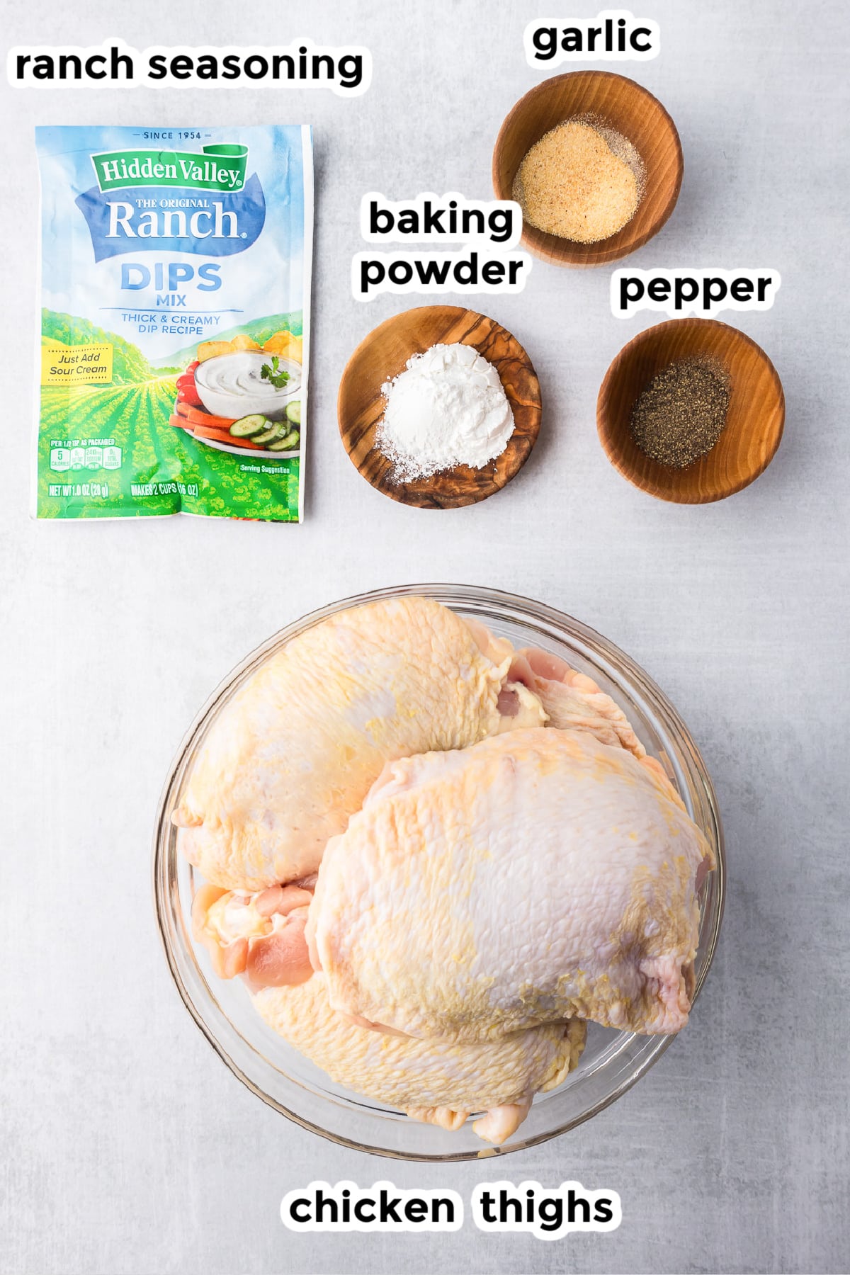 Ingredients for baked ranch chicken thighs in bowls with text labels.