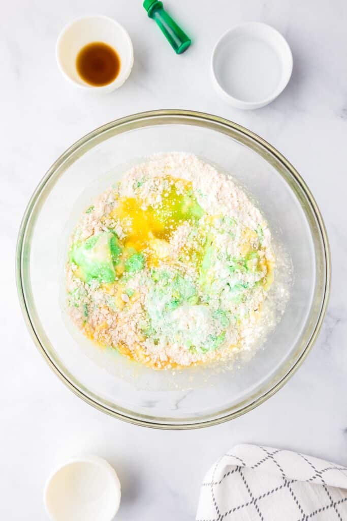 Top view of a glass mixing bowl with dry and wet ingredients being combined for pistachio bread.