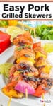 Three grilled pork skewers with chunks of juicy pork, pineapple, peppers, and onions with title text overlay at the top of the image.