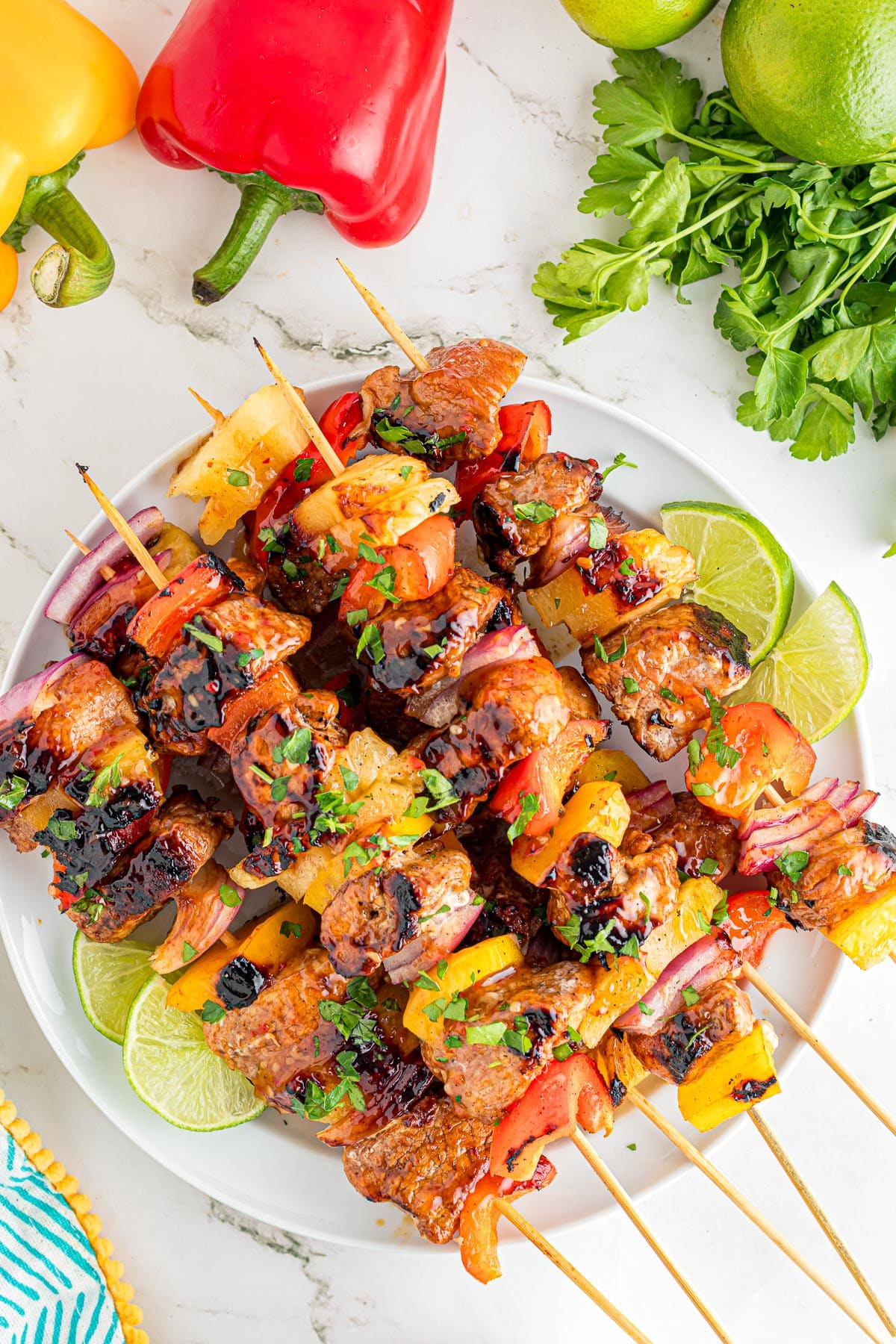 Grilled pork skewers with bell peppers, onions, and pineapple on a platter.