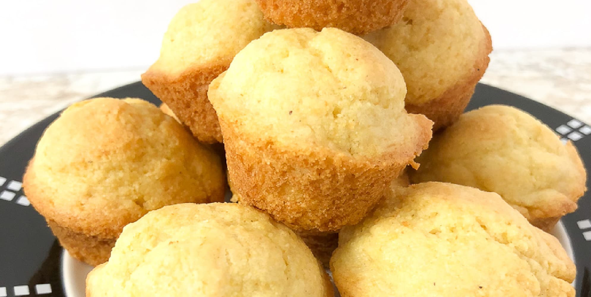 A close up view of a stack of sweet cornbread muffins piled high.