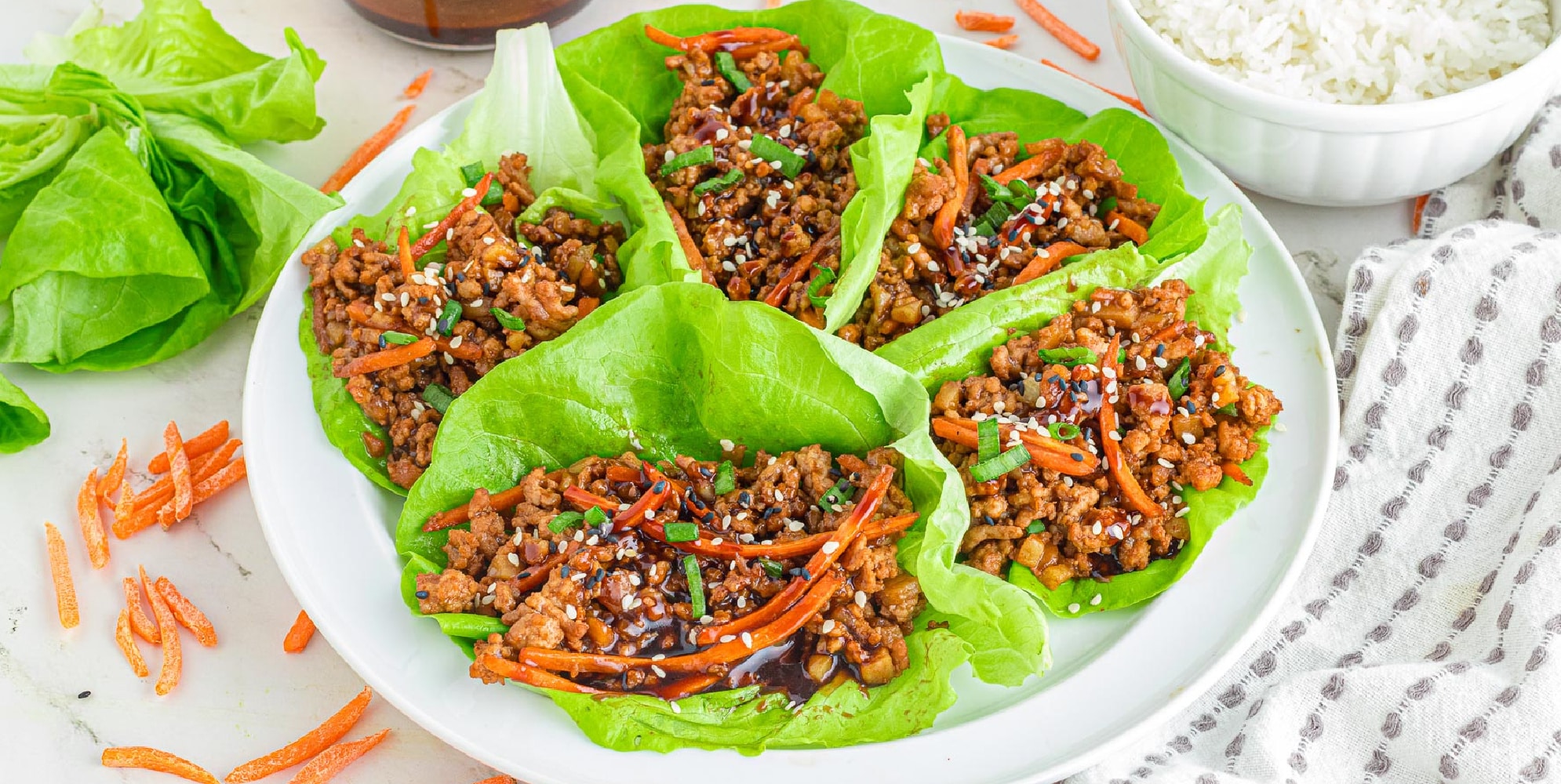 Wide view of ground pork lettuce wraps on a plate to serve.