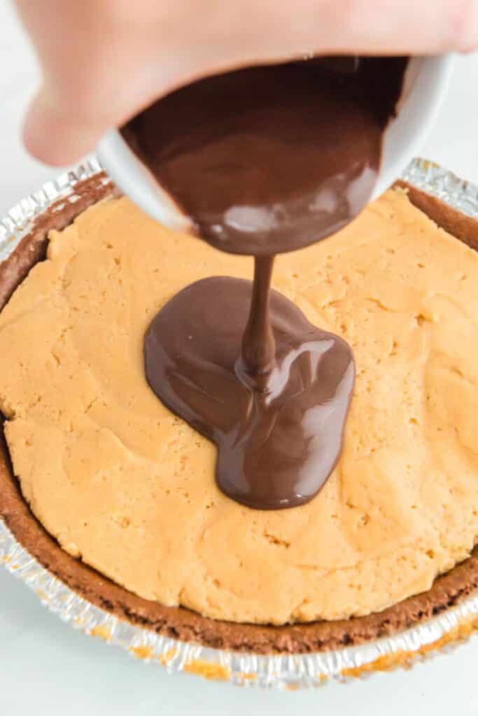 Melted chocolate being poured over top of a peanut butter buckeye pie.