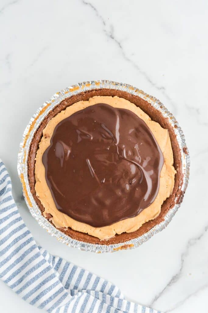 A chocolate pie crust filled with peanut butter filling topped with a topping chocolate layer for buckeye pie.