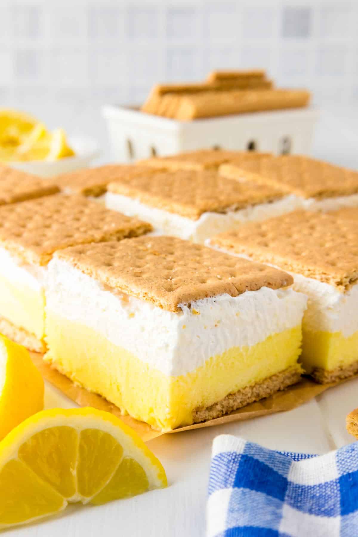 Slices of lemon smores topped with graham crackers laying on a piece of parchment paper so you can see the lemon and marshmallow cream layer.