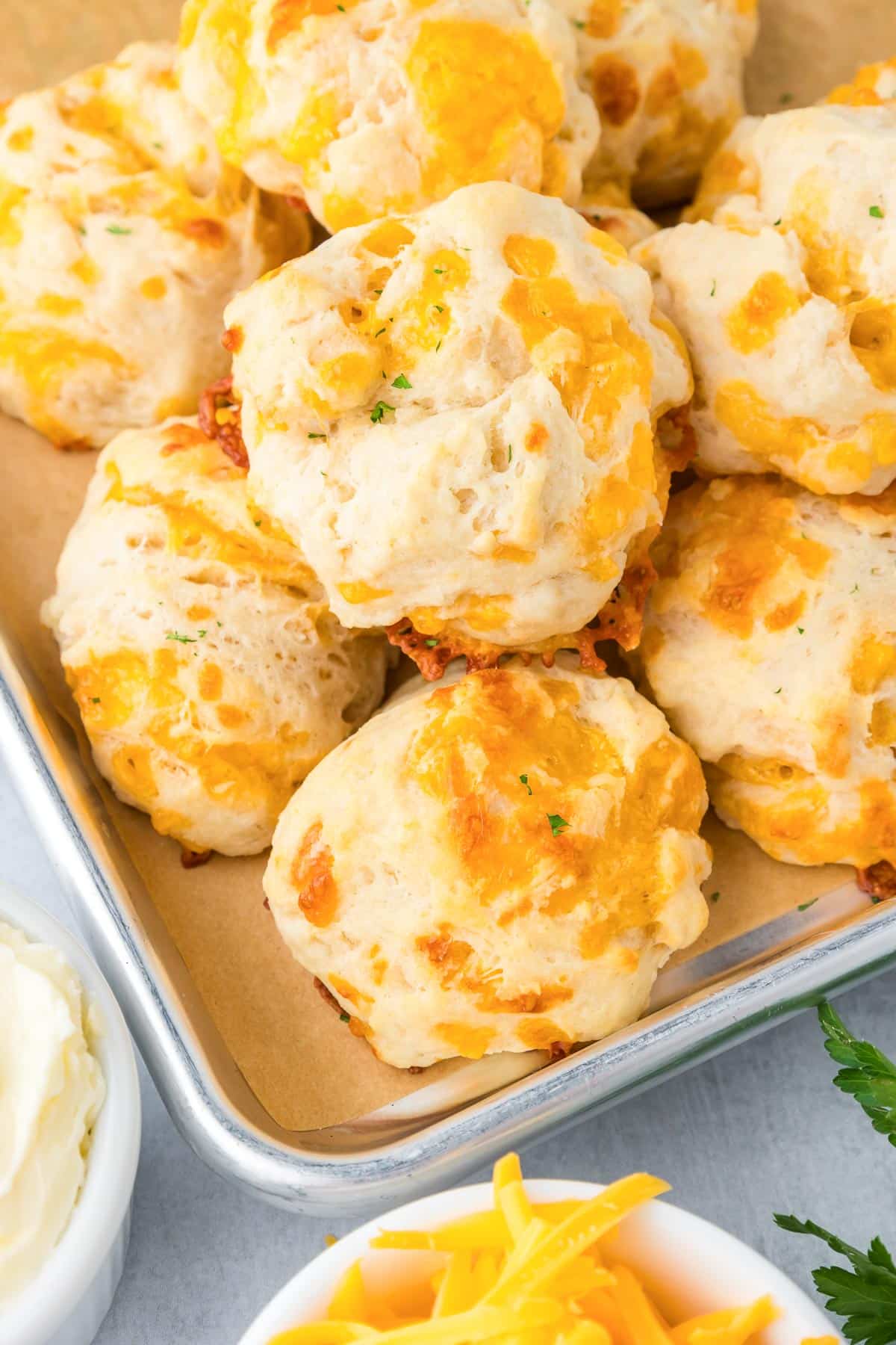 A tray of freshly baked cheddar biscuit stacked on a baking pan.