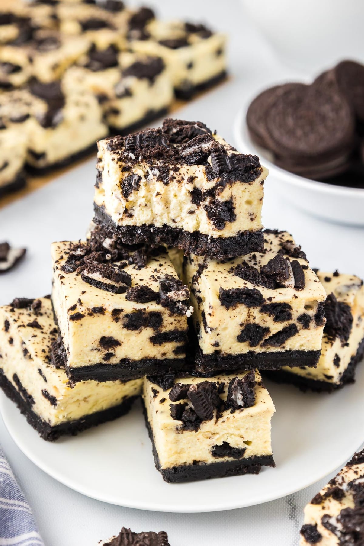 A serving plate full of Oreo cheesecake bars with the top missing a bite, and more bats in the background.