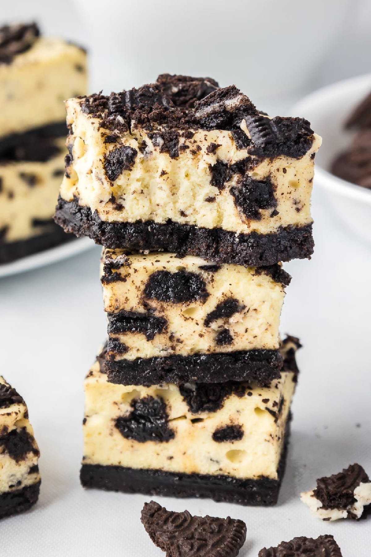 A stack of three Oreo cheesecake bars with the top bar missing a bite.