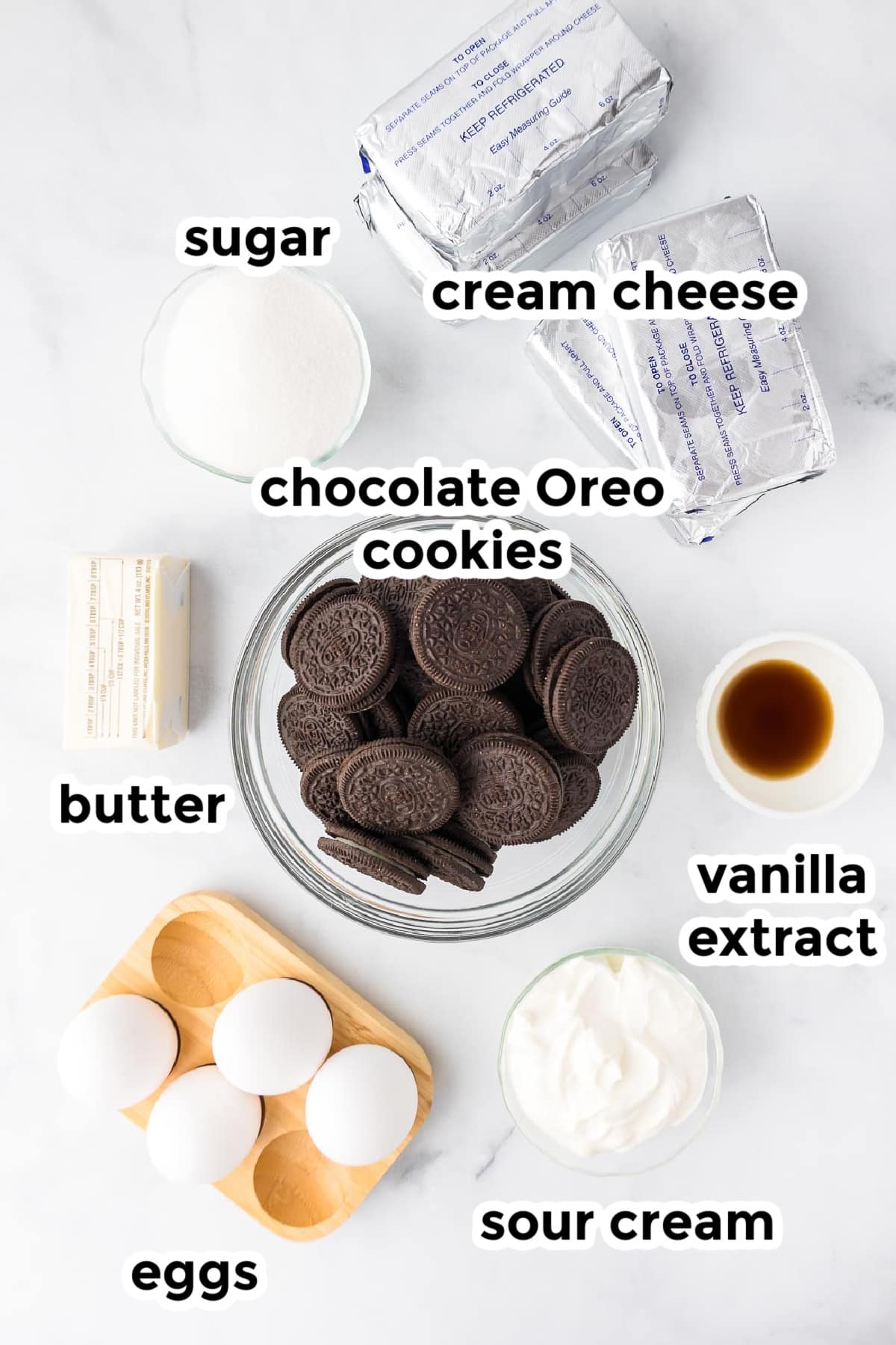 Ingredients for Oreo cheesecake bars in bowls on a counter with title text labels.