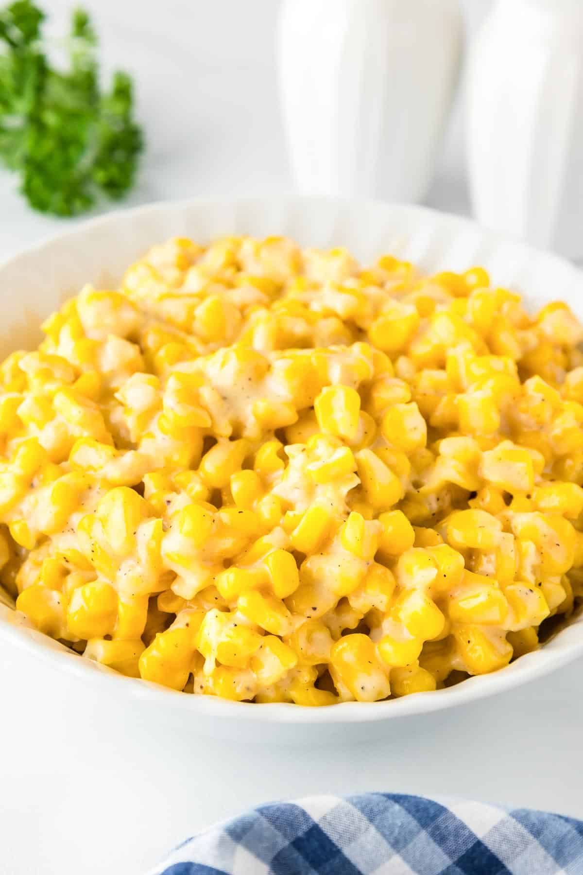 A bowl of creamy corn in a serving bowl on a table from the side.