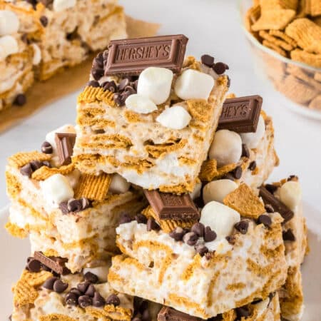 A stack of s'mores Rice Krispie treats topped with Hershey's chocolate squares, mini marshmallows, Golden Graham's cereal and mini chocolate chips.