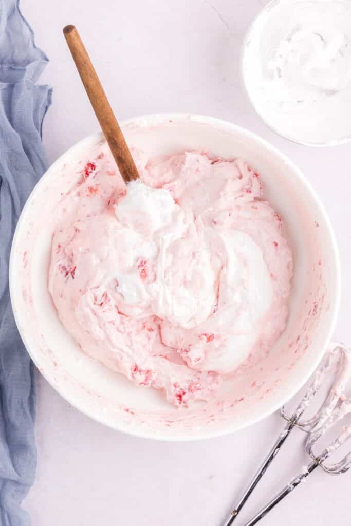 A bowl of cream cheese, marshmallow fluff and bits of strawberries whipped together.
