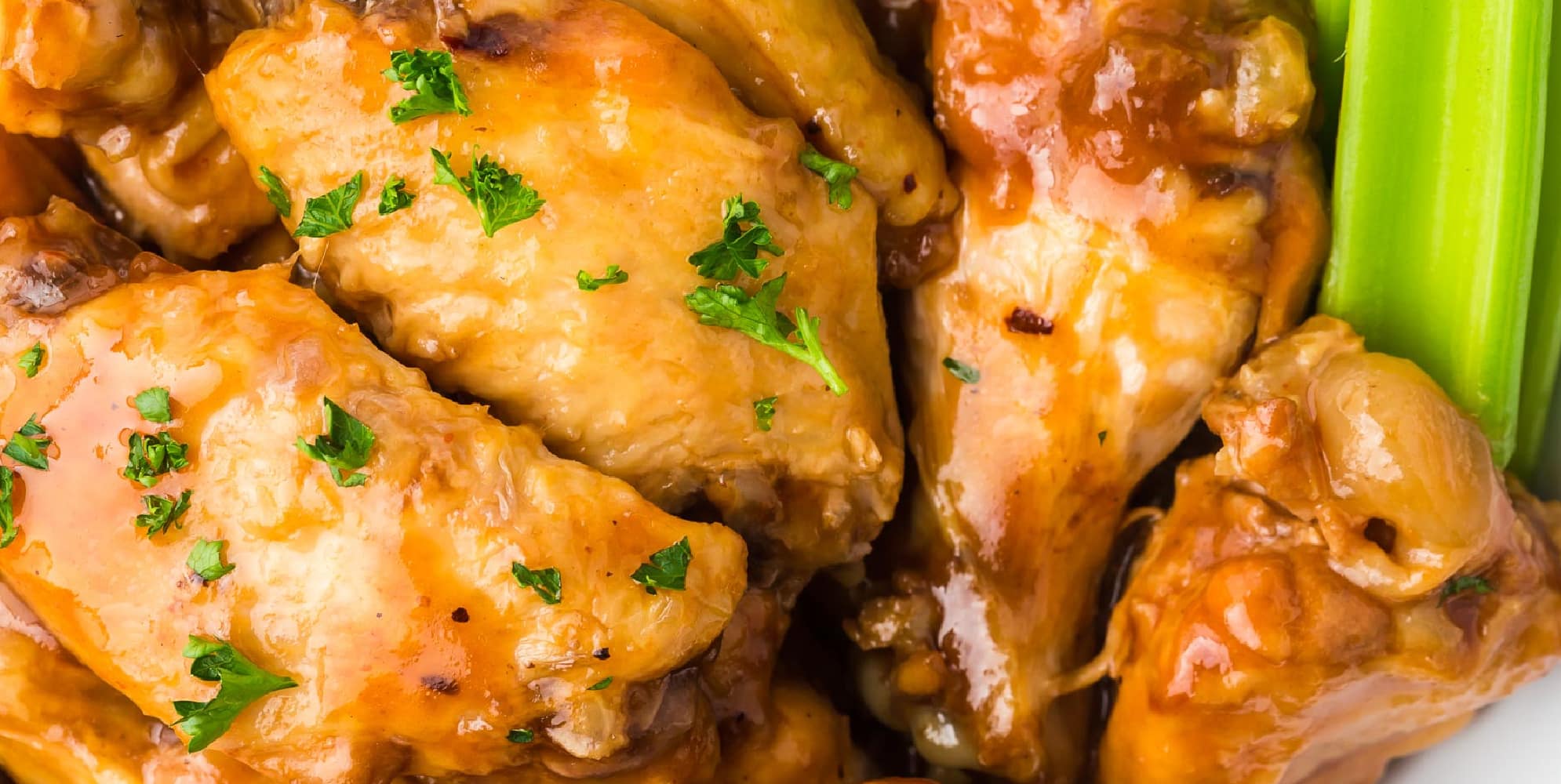 Close-up of bbq sauced chicken wings next to sliced celery.