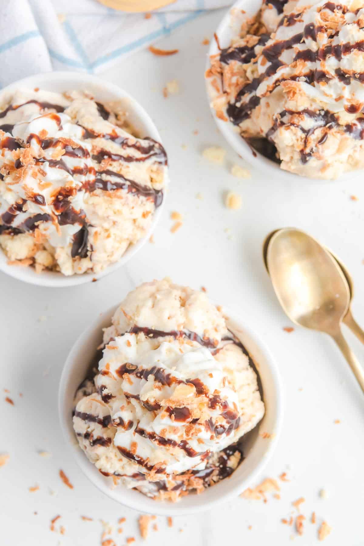 Three bowls of samoa ice cream topped with chocolate and coconut flakes on a counter from overhead.