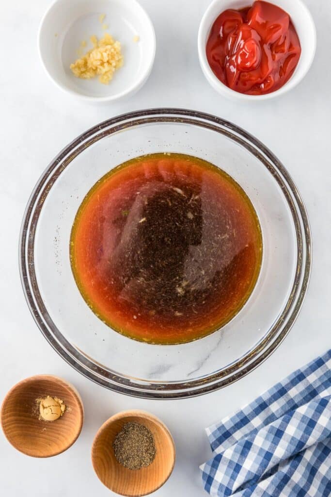 A clear glass bowl with ingredients being mixed to make a sweet and sour sauce.