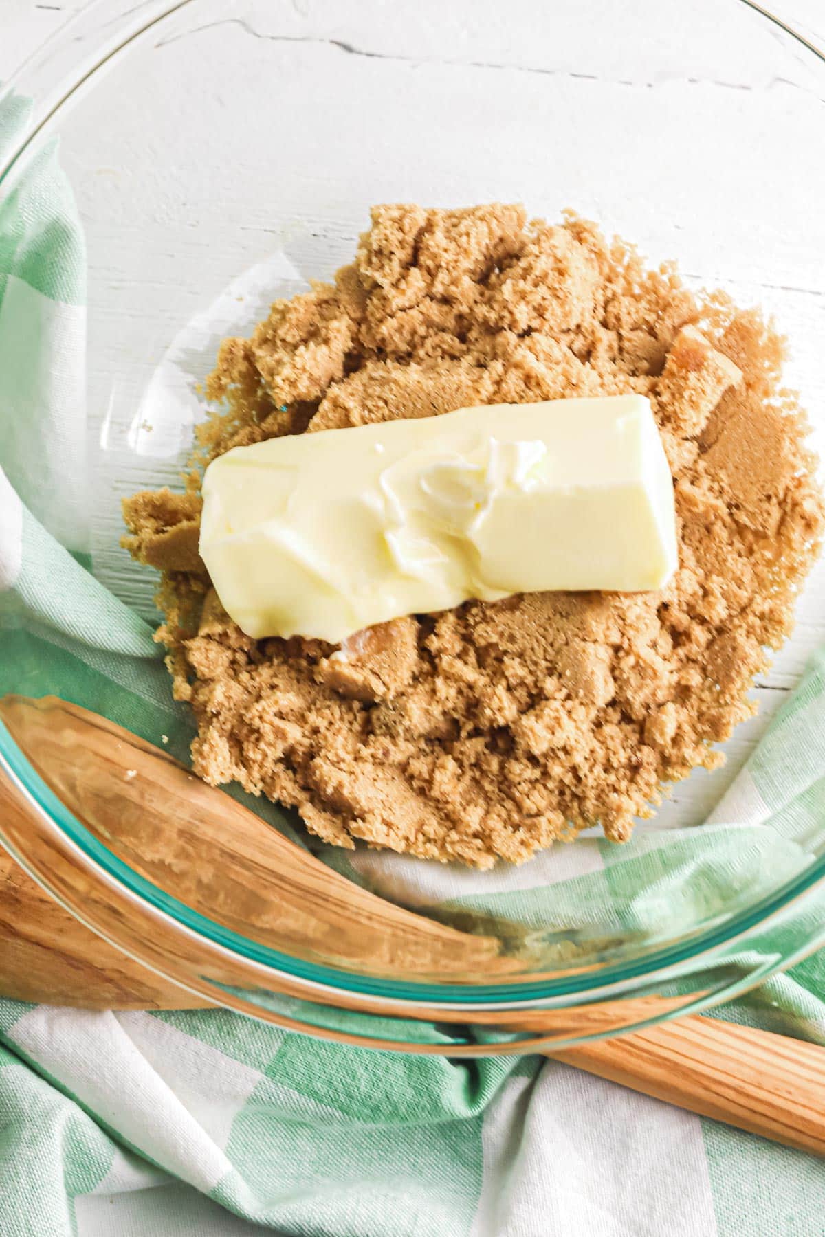 A glass bowl with brown sugar softened butter being mixed for chocolate chip toffee cookie dough.