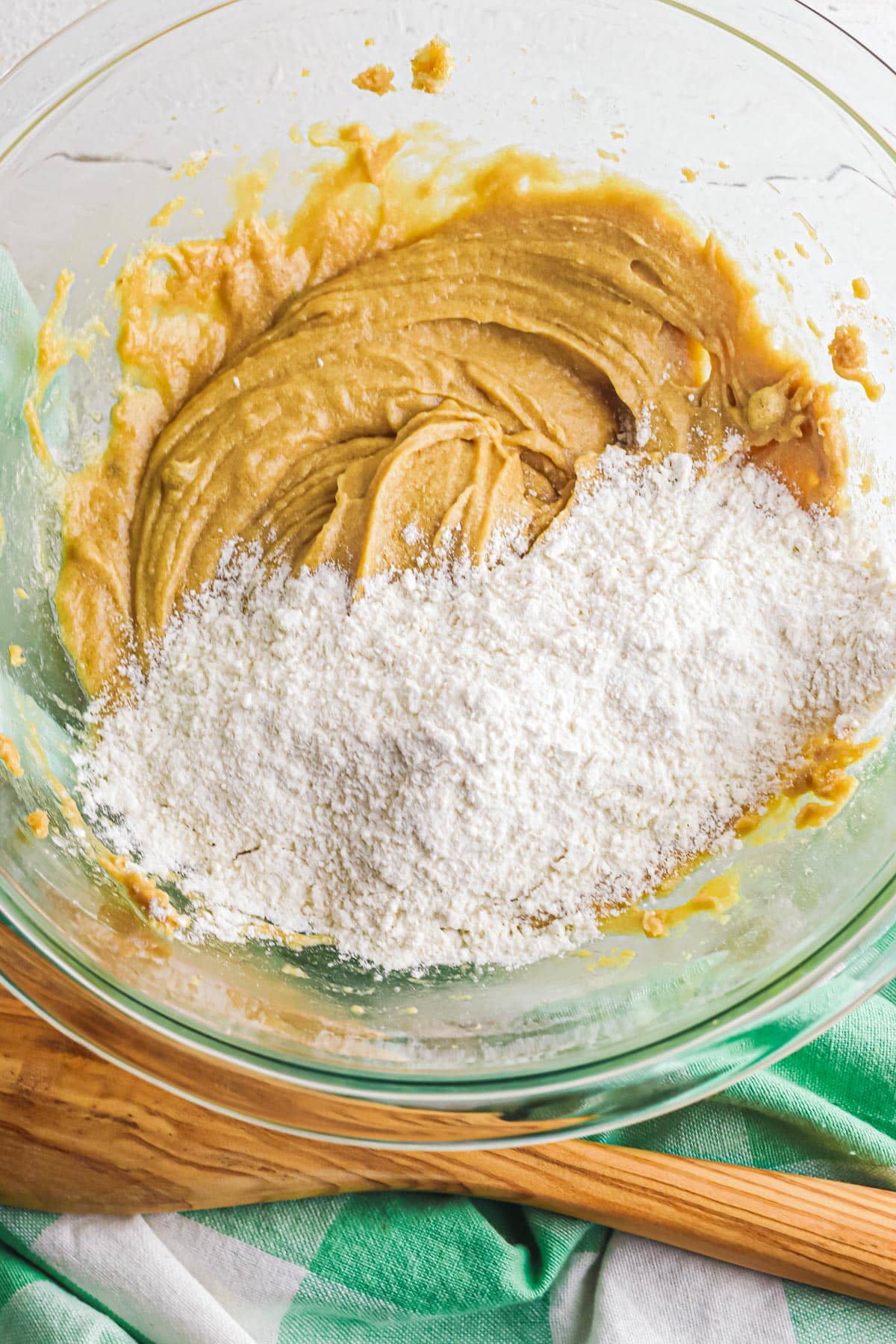 Flour mixture being added to the wet ingredients to form a cookie dough for toffee cookies in a bowl.