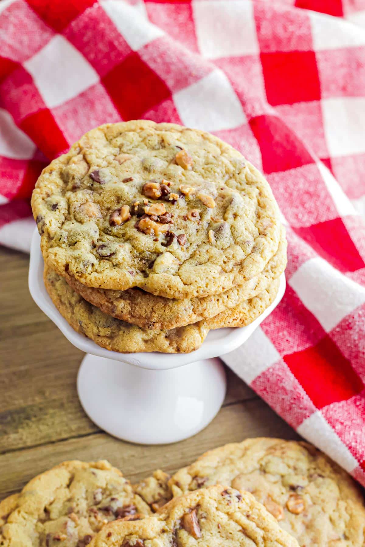 A stack of chocolate chip toffee cookies on a white pedestal plate stacked from overhead.