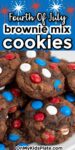 A close-up of chocolate brownie mix cookies with red, white, and blue candy pieces with title text saying Fourth Of July Brownie Mix Cookies across the top of the image.