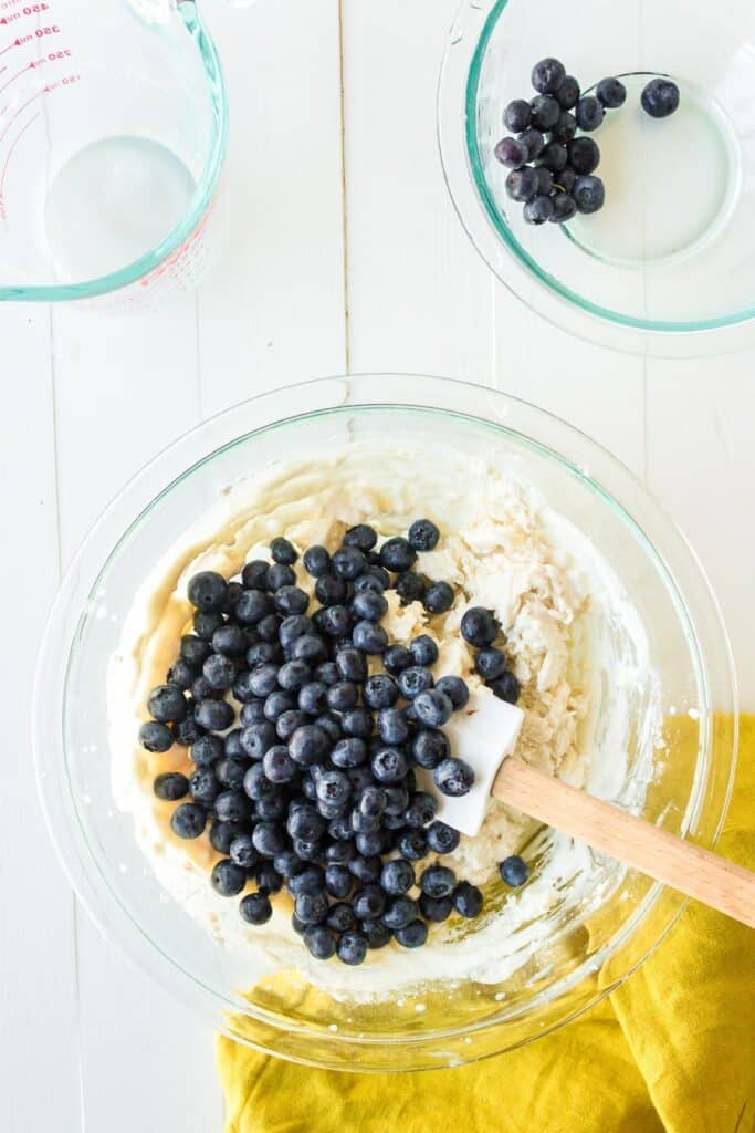 A mixing bowl with blueberries being mixed into a biscuit dough.