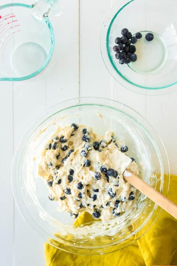 A glass mixing bowl with blueberry biscuit batter after folding in blueberries.