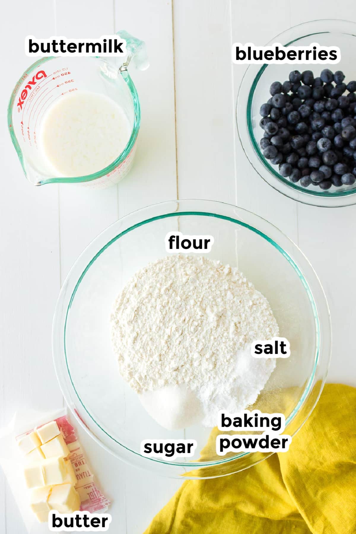 Ingredients for blueberry biscuits in bowls with text labels.