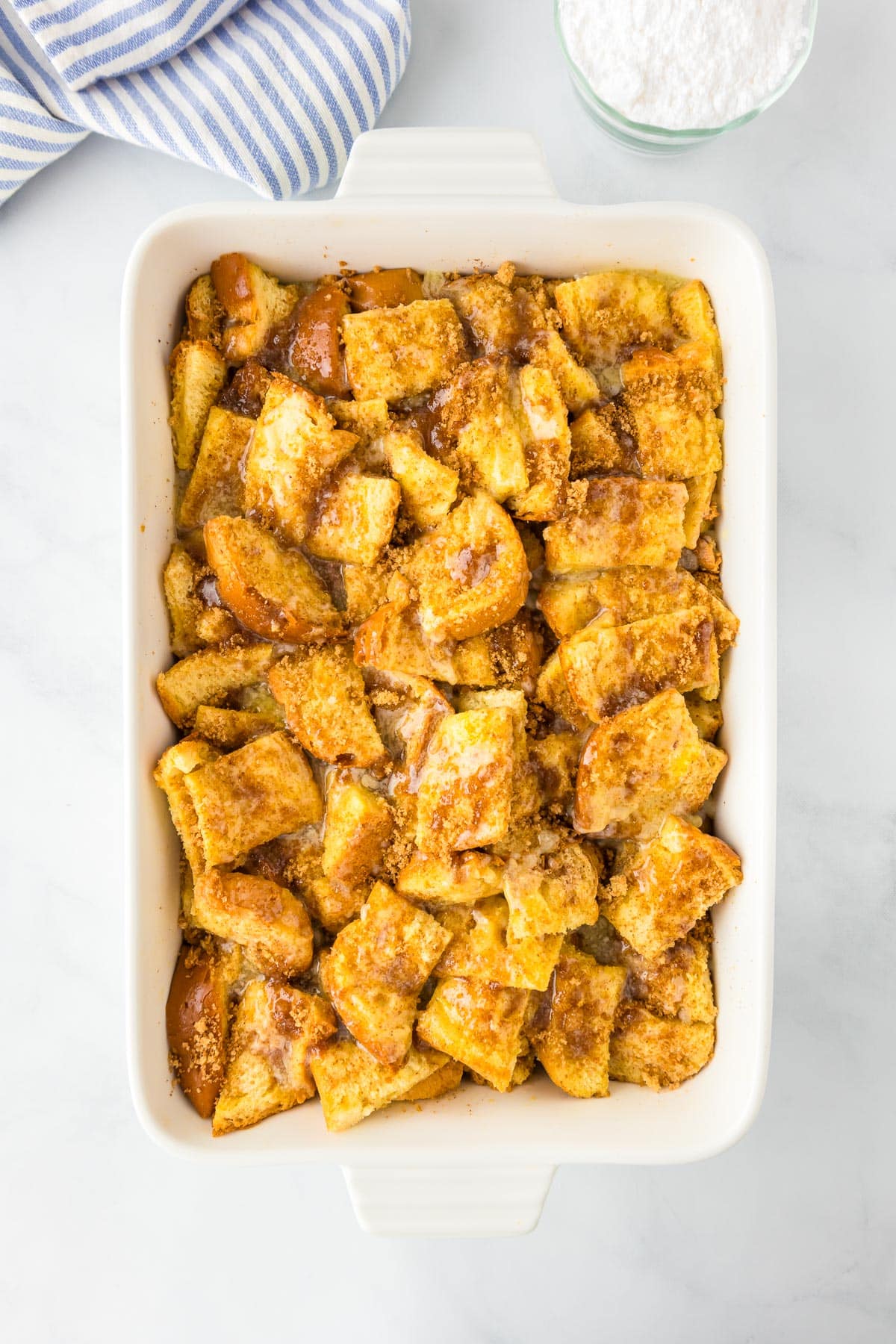 A casserole dish filled with brioche french toast casserole topped with the cinnamon crumble topping before baking.