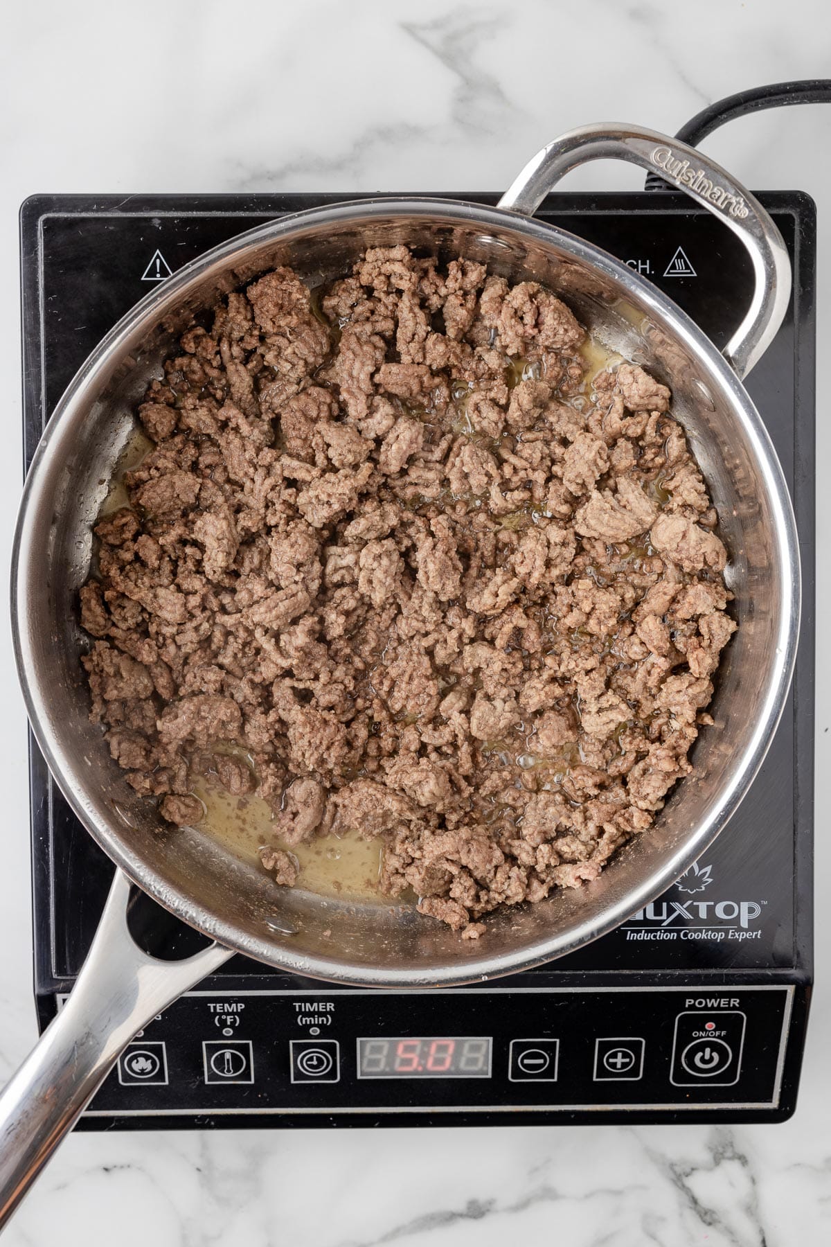 Cooked ground beef in a pan on a burner from overhead.