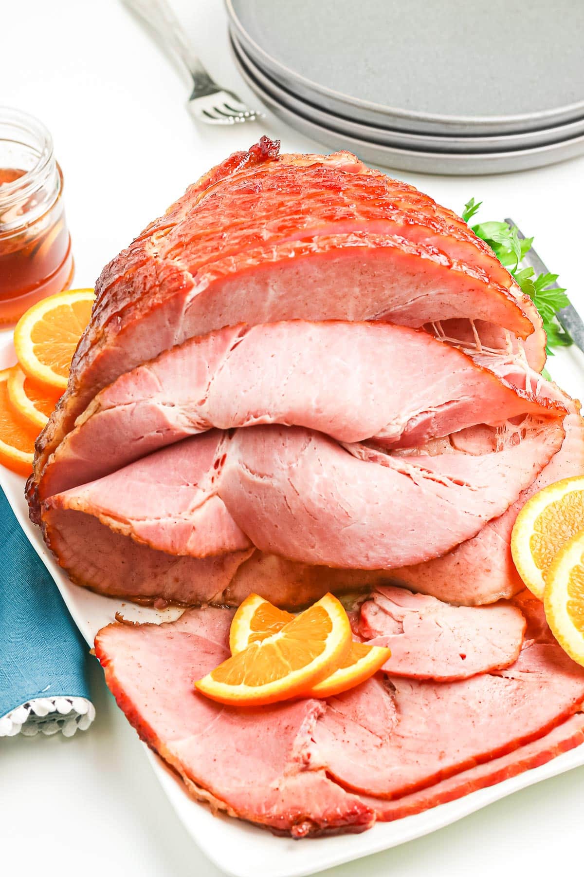 A plate with sliced glazed ham garnished with orange slices