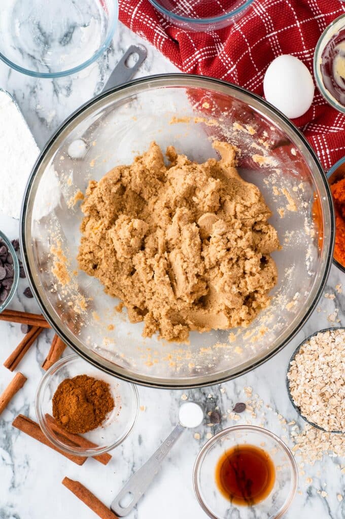 A glass bowl filled with butter, sugar and brown sugar mixed to make oatmeal pumpkin cookie dough.