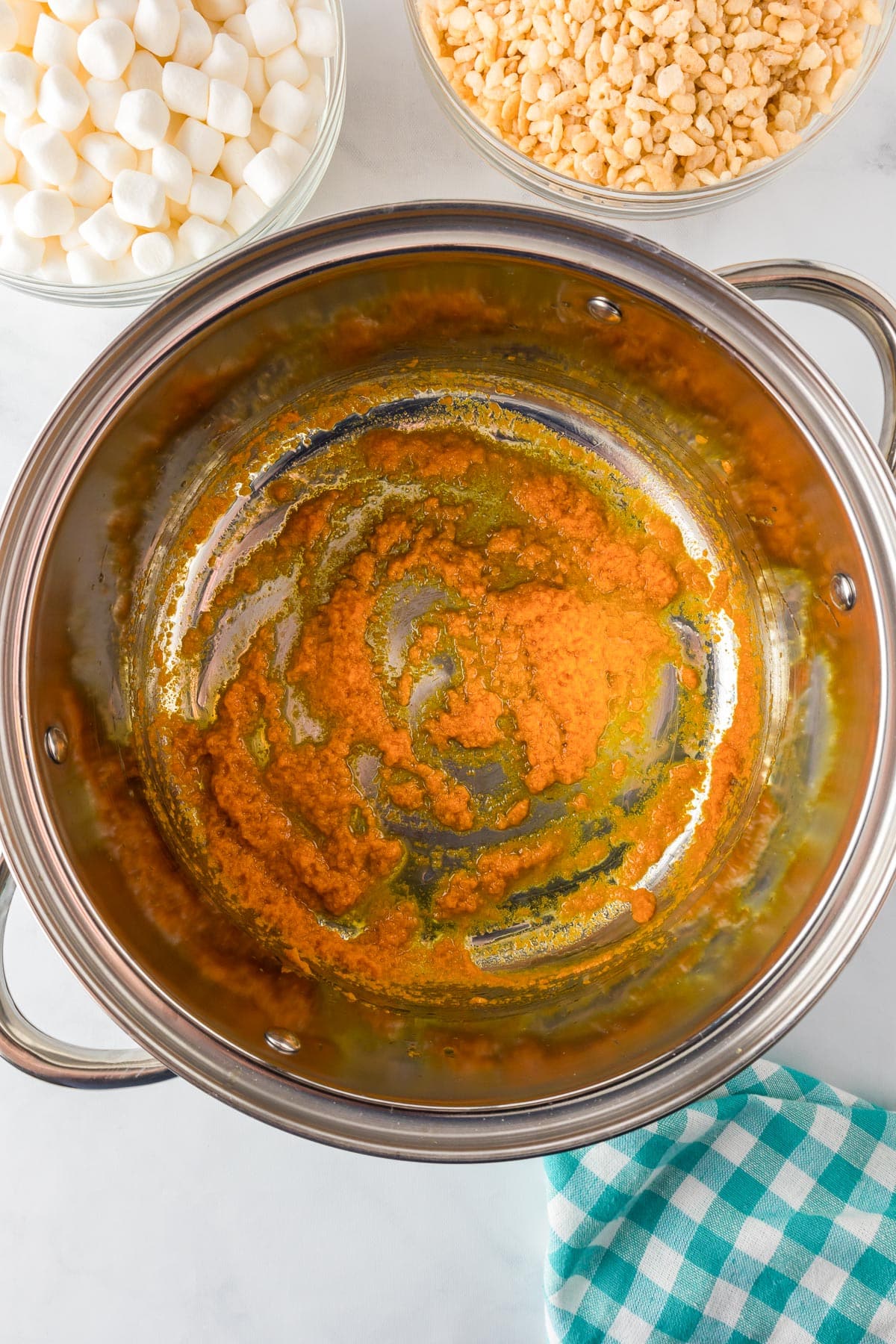 A pot filled with melted butter and pumpkin being mixed together.