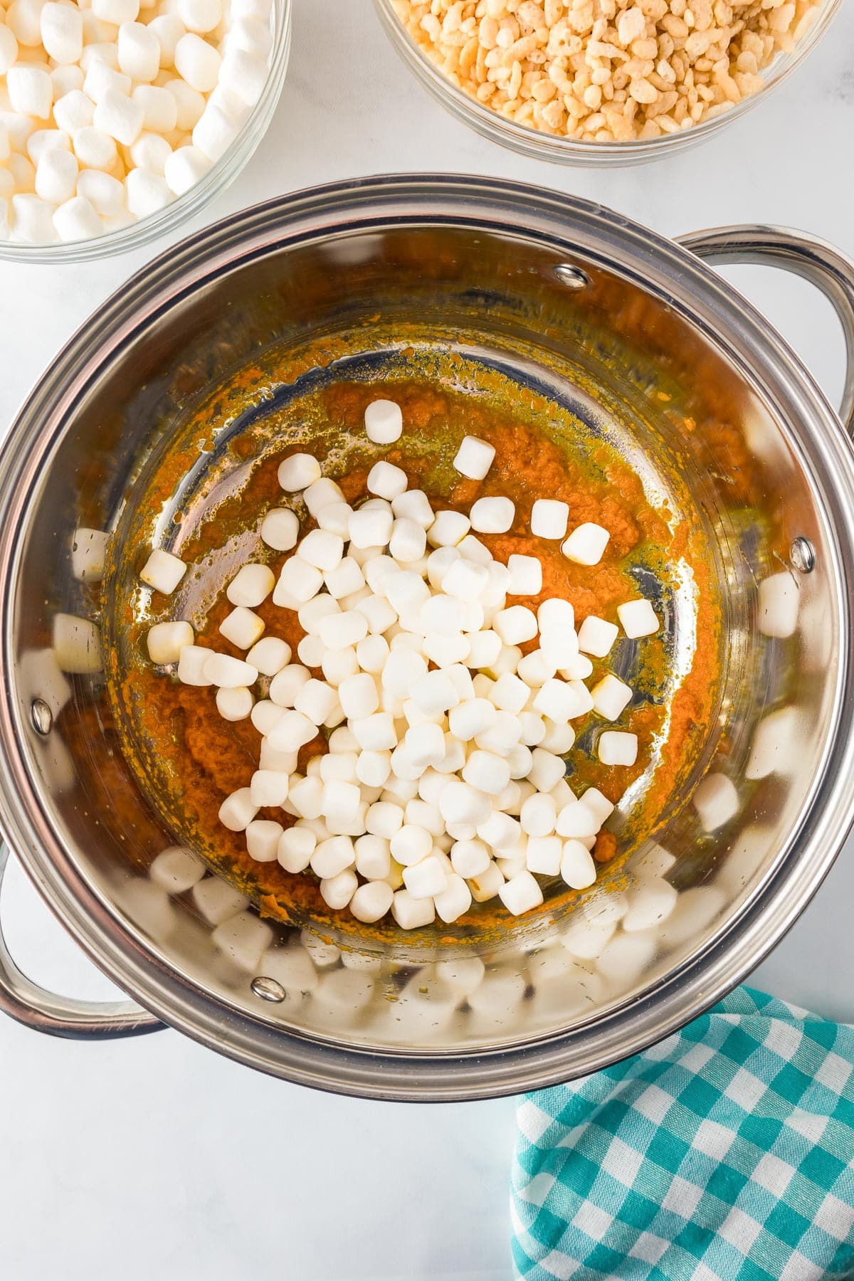 A saucepan containing partially melted butter, pumpkin and mini marshmallows.