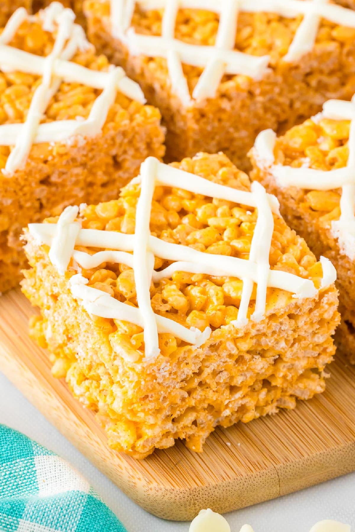 Close-up of several Pumpkin spice rice crispy treats topped with white chocolate on a cutting board close up on the front piece.