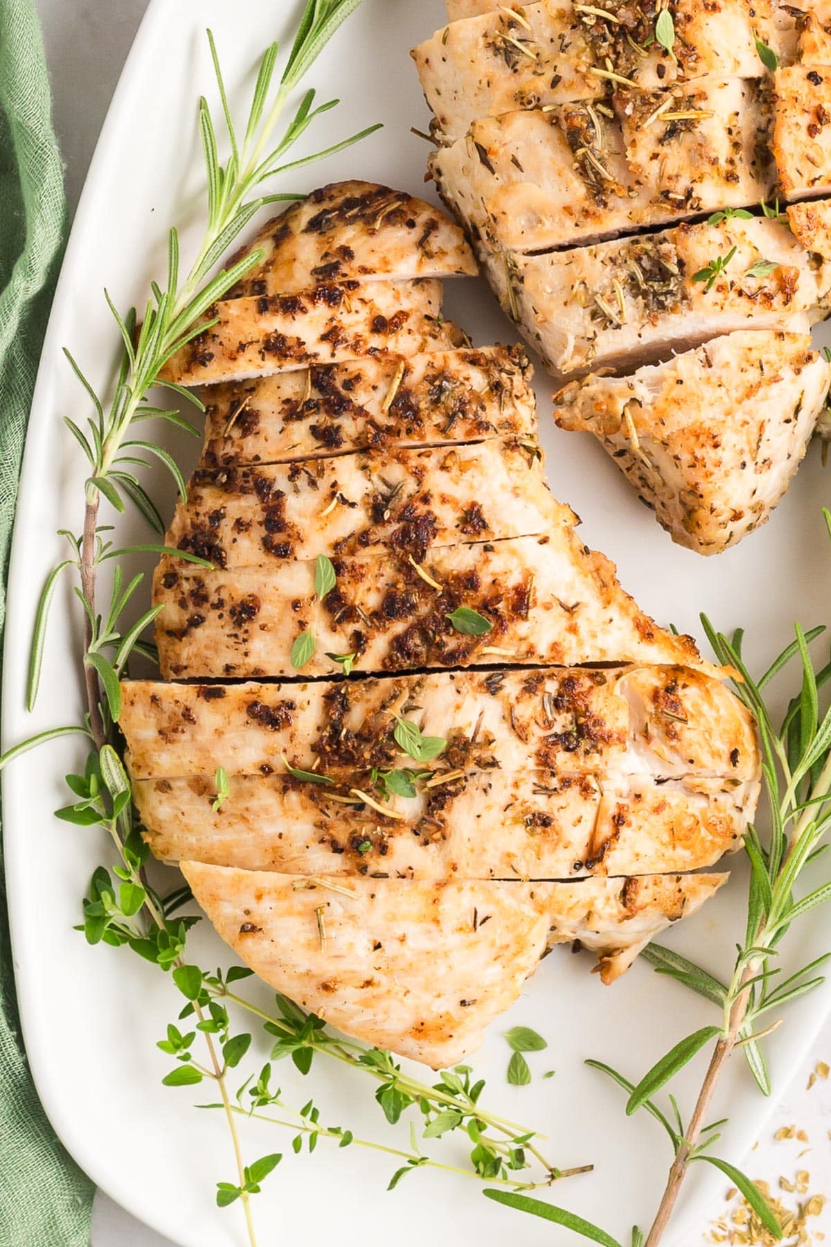 A close-up of seasoned roasted turkey tenderloin sliced on a platter garnished with fresh rosemary.