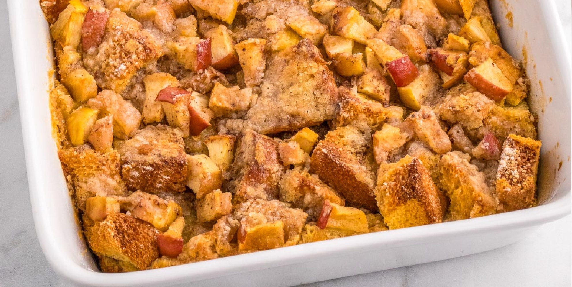 A wide view of a baked apple french toast casserole in a baking pan .