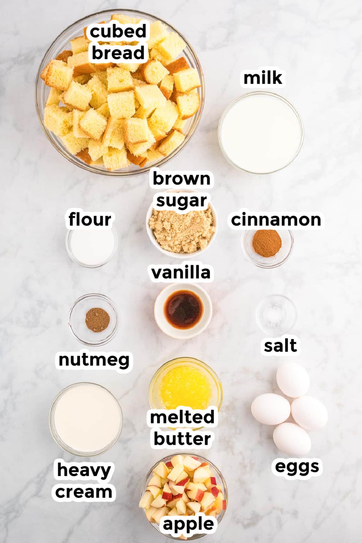 Ingredients on a table in bowls for making apple french toast casserole with text ingredient labels.