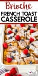 A casserole dish of brioche French toast casserole topped with powdered sugar, raspberries, and blueberries looking at just the edge of the pan with title text across the top of the image.