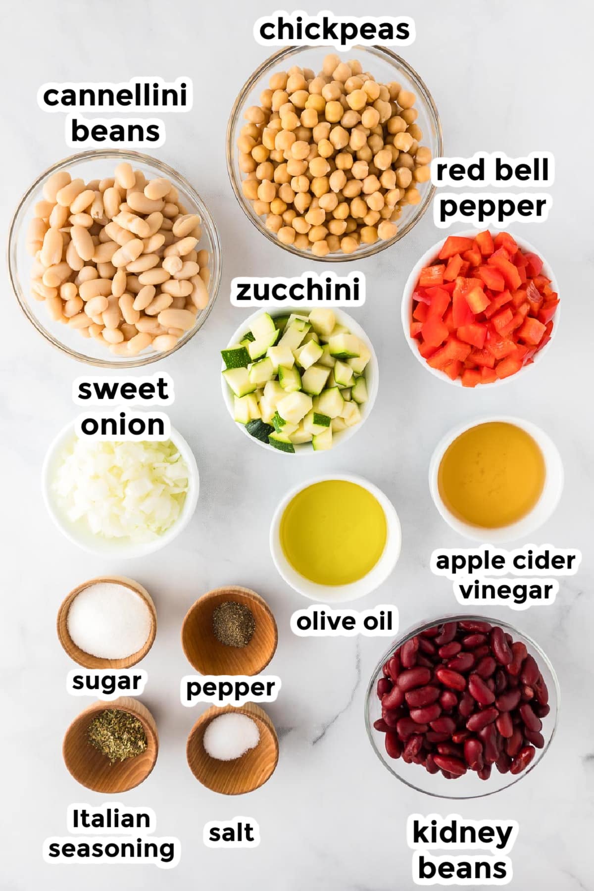 Ingredients for chickpea bean salad in bowls on a counter with text labels.