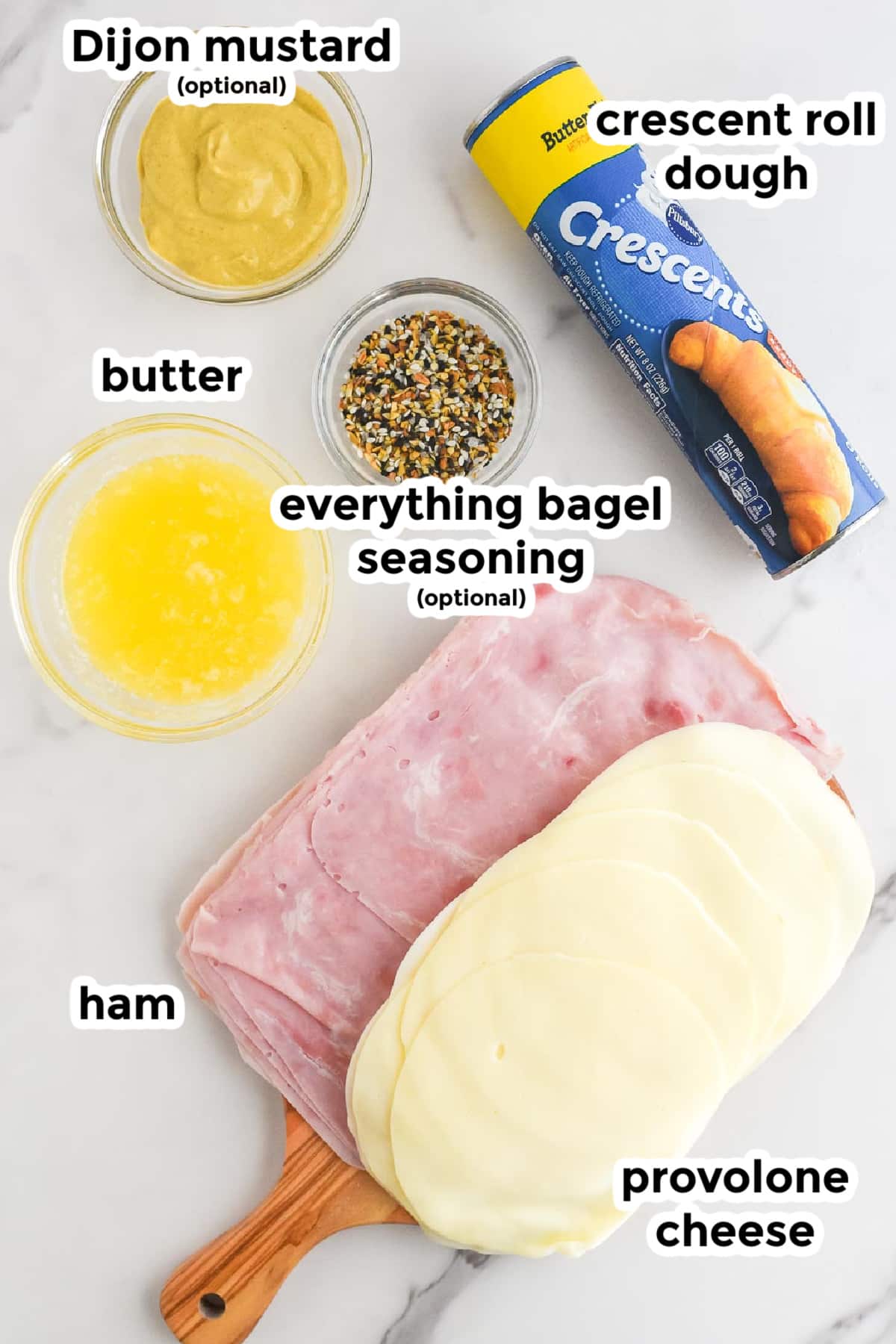 Ingredients for ham and cheese pinwheels on a counter in bowls with text title labels.