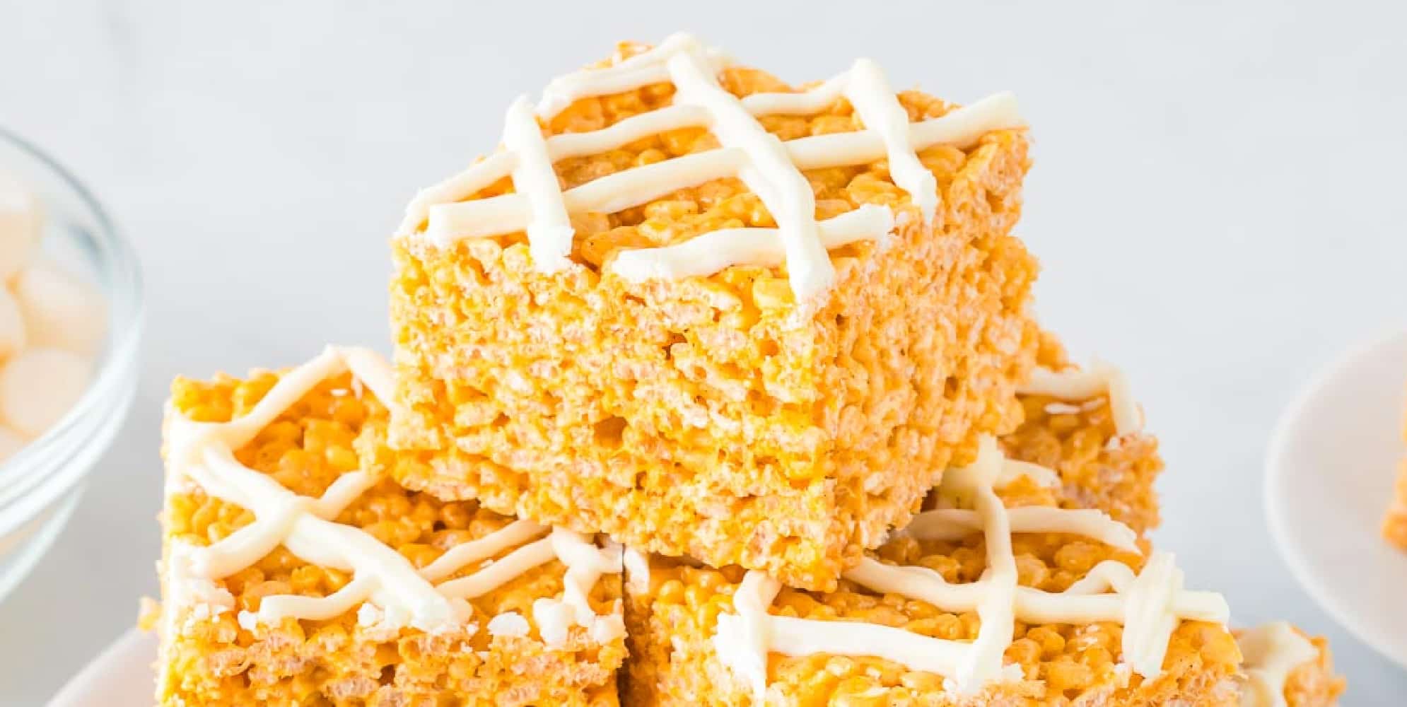 Wide view of a stack of three crispy rice treats drizzled with white chocolate.