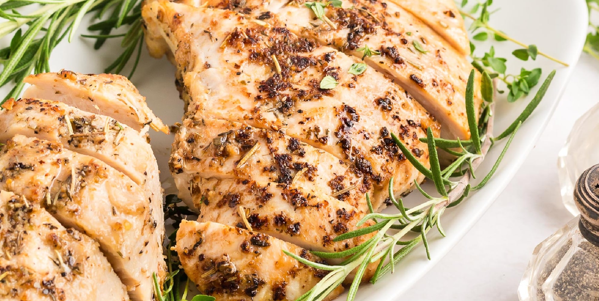 Wider view of two roasted turkey tenderloin pieces sliced on a platter close up.