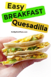 A hand holding a stack of breakfast quesadillas filled with scrambled eggs, cheese, and broccoli. Text overlay reads "Easy Breakfast Quesadilla."