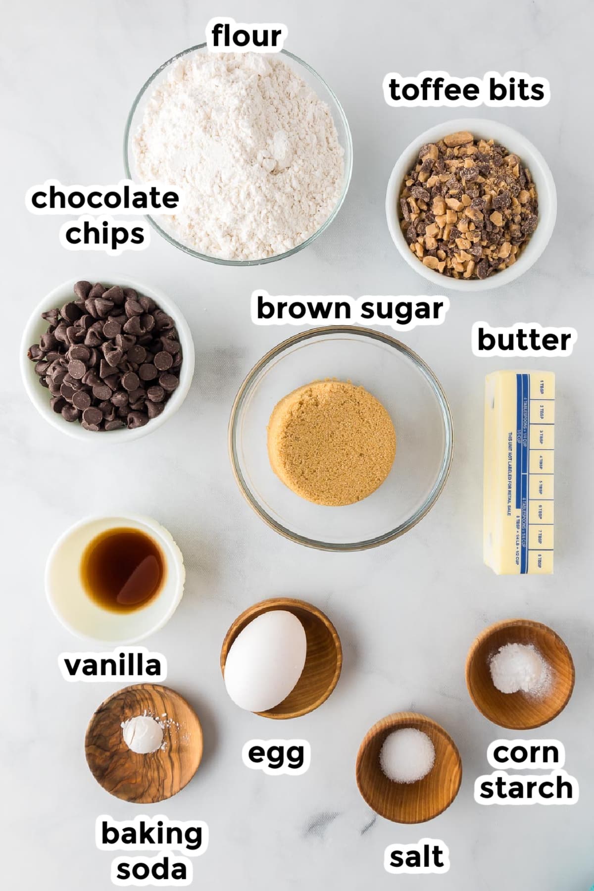 Ingredients for toffee chocolate chip cookies on a counter in bowls with text title labels.