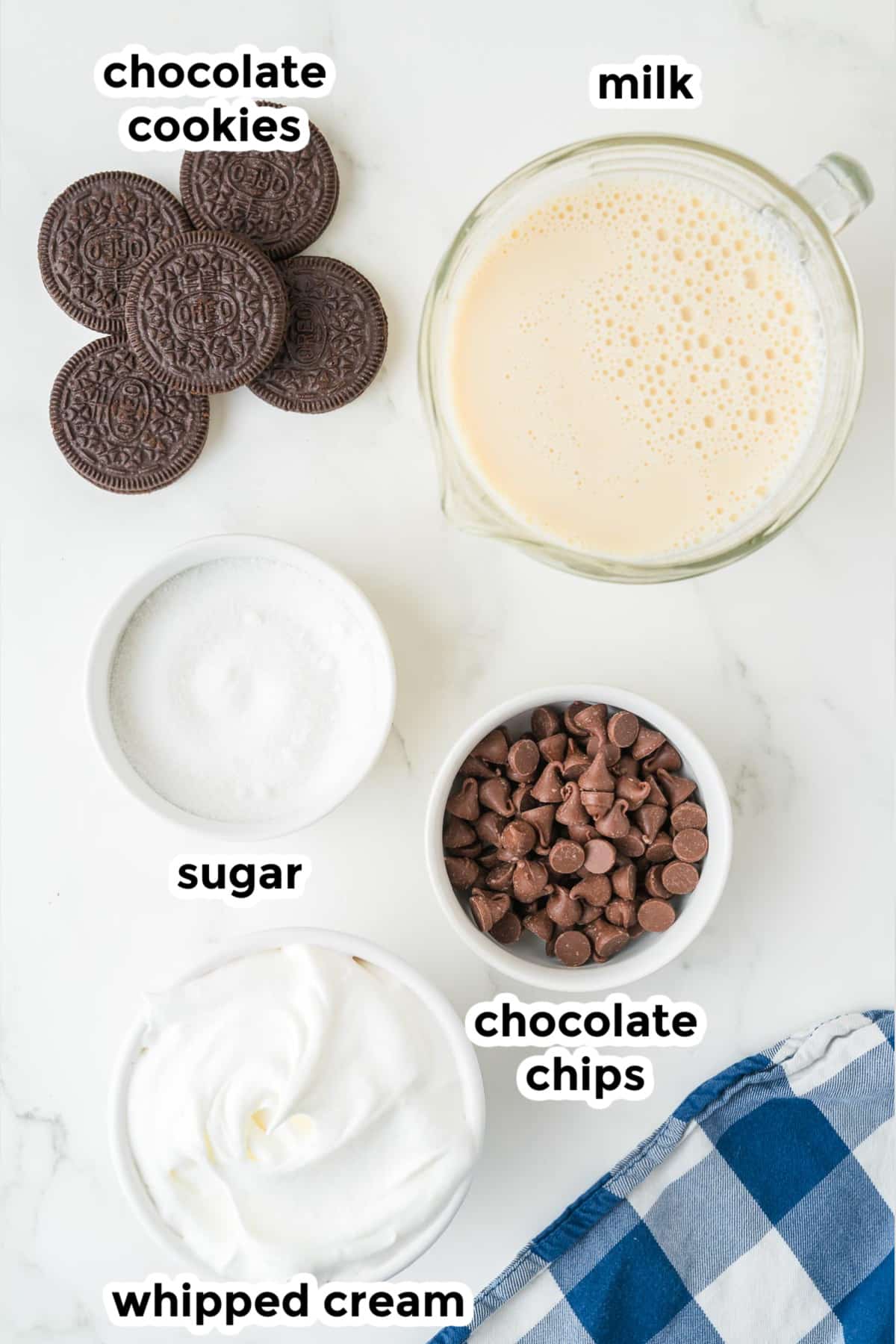 Ingredients for Oreo hot chocolate in bowls on a counter with text labels.